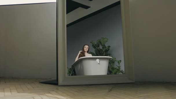 Ride by the camera. A beautiful girl with long hair relax in a white bath full of hot water. Young woman with long hair in the bathroom — Stock Video