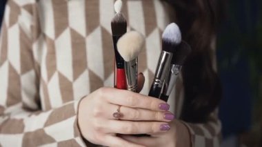 Kadın ellerinde kozmetik fırçalar kümesinin bir yakın çekim. Bir genç kadın makyaj sanatçısı makyaj için bir fırça tutar. Son saatlerinde yanında bulunanlar için aksesuarlar