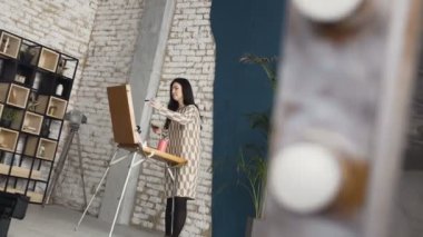 İçinde genç bir kadın bir resim arkasında, atmosferik bir atölye bir şövale bir tuval üzerine boyar. Sanat Akademisi ve okul çizim. İlham. Yetenek