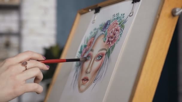 Крупный план женских рук, который рисует эскиз лицевой диаграммы. Девушка-художник рисует набросок на графиках. Молодая женщина в яркой студии рисует график лица, используя — стоковое видео