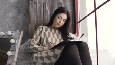 Profesyonel makyaj sanatçısı yüz grafik kozmetik ve fırça palet tonları kullanarak suluboya kağıdı üzerinde boyar. Elbiseli kadın sanatçı evde tuval üzerine resim boyaları