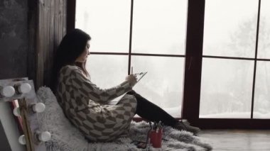 Genç esmer kadın pencere pencere ve çizimlerine içinde çizim yakınında oturuyor. Çizim penceresi elbiseli kadın sanatçı esin kaynağı oldu