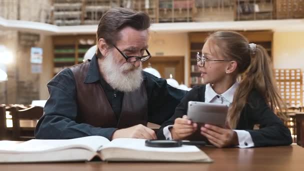 Portrait amusant de vieux grand-père barbu estimé qui tient sa tête après sa belle petite-fille adolescente lui a montré comment utiliser ebook — Video