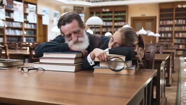 Moe bebaarde senior man en zijn tiener mooie kleindochter slapen op boeken in de bibliotheek — Stockvideo