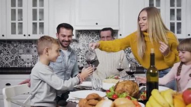 Güzel genç anne Şükran Günü yemeğinde oğluna kiraz suyu dolduruyor.