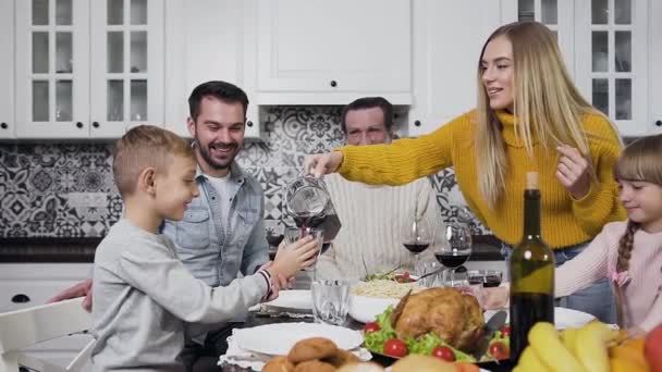 Bastante joven madre vertiendo jugo de cereza en el vaso a su hijo durante la cena de Acción de Gracias — Vídeos de Stock