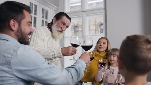 Sorridente nonno anziano che tintinna il vetro con tutti i membri di famiglia durante celebrazione il giorno del Ringraziamento — Video Stock