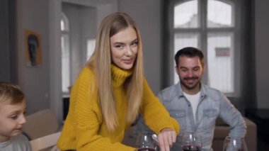 Sarı örgü süveter giyen güzel sarışın anne Şükran Günü 'nde ailesi için hindiyi dilimlerken kameraya bakıyor.