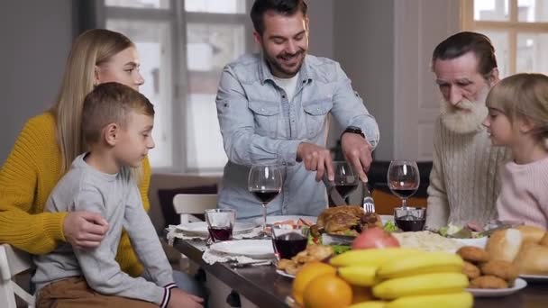 Lächelnder bärtiger Mann schnitzt seiner süßen Tochter beim Familienessen ein kleines Stück Truthahnbraten — Stockvideo