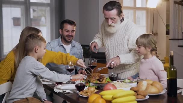 Gerespecteerde senior grootvader snijdend traditionele gebraden kalkoen tijdens de viering Thanksgiving dag — Stockvideo