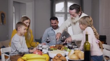 60 yaşındaki sakallı dedesinin aile yemeği masasında toplanması için lezzetli bir hindiyi oyması.