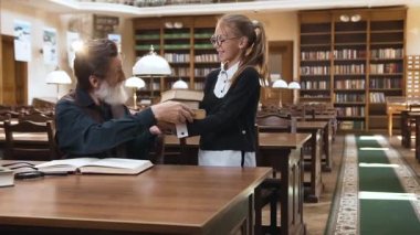 Sevimli yaşlı sakallı dedesinin çekici portresi. Büyüleyici gülümseyen torununu kütüphanede ona kitap getirirken öpüyor.