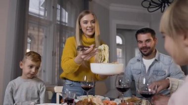Sevgili anne aile yemeği sırasında tatlı kızı için lezzetli spagetti koyuyor.
