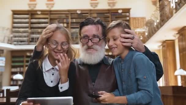 Lächelnder, glücklicher Opa mit Enkeln, die fröhlich ihre gemeinsame Zeit in der Bibliothek verbringen — Stockvideo