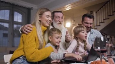 Yetişkin ve çocuklardan oluşan sevimli bir aile masada oturmuş video görüşmesi sırasında bilgisayar engelleyicileriyle veda ediyorlar.