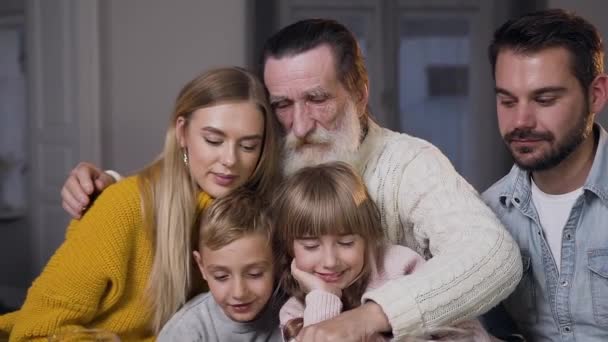 Счастливый бородатый мужчина обнимает всю свою привлекательную радостную семью и смотрит в камеру — стоковое видео