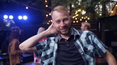 Yakışıklı 25-30 'lu yaşlarda gülümseyen ve arka planda dans eden bir adam.