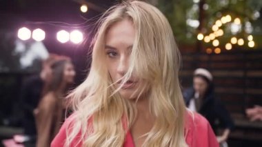 Arkadaşları partide eğlenirken ve dans ederken kameraya gülümseyen uzun siyah saçlı beyaz bir kadının yakın plan fotoğrafını çek.