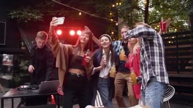 Mutlu genç erkek ve bayan arkadaşlar selfie için poz veriyorlar yaz partisinin tadını çıkarıyorlar dans ediyorlar, alkol içiyorlar sosyal medyada hafta sonunu paylaşıyorlar.