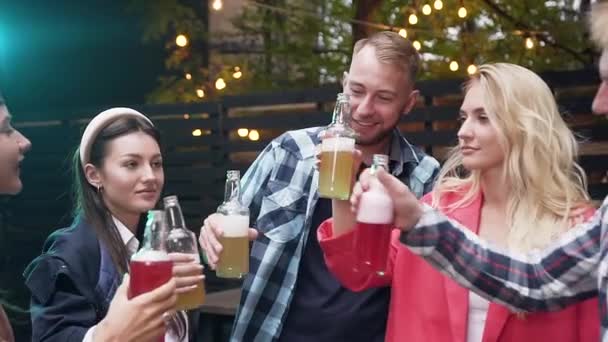 Gruppe kaukasischer Freunde mit einem Toast auf Glasflaschen mit verschiedenen Getränken, Bier trinken und Gartenhaus-Party in der Nacht am Wochenende genießen — Stockvideo