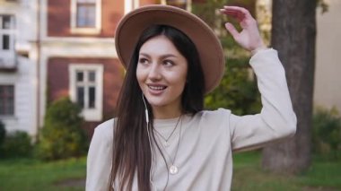 Yakışıklı, güler yüzlü, şık şapkalı, güzel zengin evleri olan ve kulaklıkla müzik dinleyen modern bir kadın.