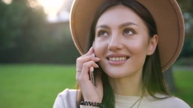 Şık şapkalı neşeli, sevimli, güzel bayan dışarıda akıllı telefondan konuşuyor.