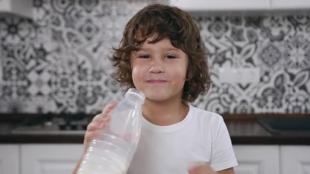 Menino de 5 anos com cabelos castanhos encaracolados sentado na mesa da cozinha com tigela com flocos de milho e leite para beber — Vídeo de Stock