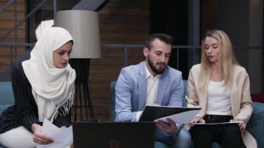Çekici genç, başarılı erkek ve kadın iş arkadaşları ortak iş projeleri altında yeni modern ofisteki yumuşak koltuklarda oturuyorlar.