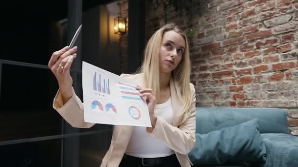 Впевнена, що досвідчена молода блондинка бізнесменка пояснює графіки та діаграми своїм діловим партнерам у сучасному офісі — стокове відео