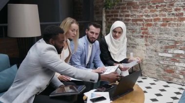 Hoş görünümlü tecrübeli genç iş adamları ve kadınlar modern ofis odasında birlikte çalışıyorlar.
