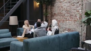 Farklı etnik kökenlere mensup çalışanlar mutlu bir şekilde gülümsüyor. Haritalarla bir sürü finansal döküman dağıtıyor ve ortak çalışmalarında zaferi kutluyorlar.