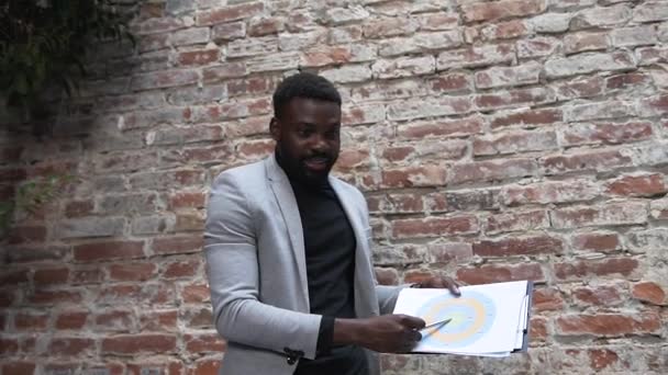 Handsome afro american businessman uses financial document with graphs to familiarization their multi ethnic business partners the results of research which brainstorming in office boardroom — Stock Video