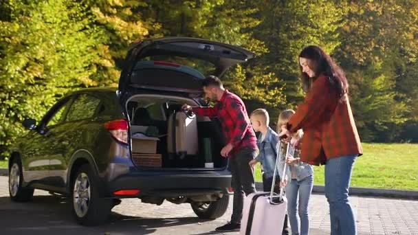 Adorable satisfied family unloading from the cars trunk suitcases and boxes during relocation to the new house — Stock Video