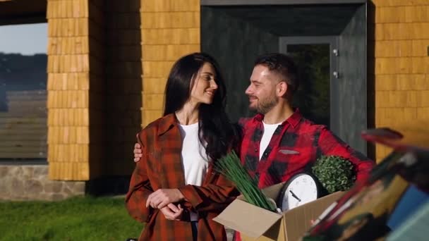 Attractive smiling man and woman standing near beautiful house and posing on camera — Stock Video