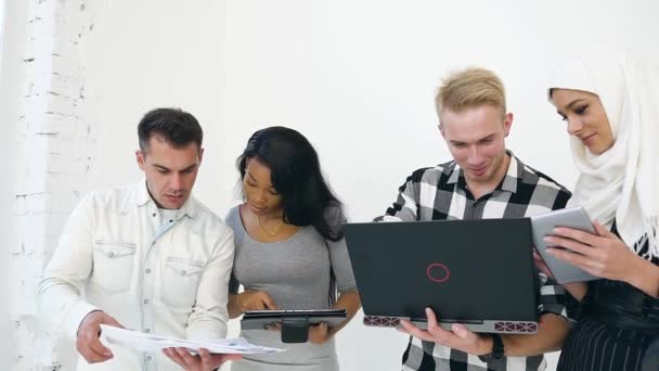 Dwie pary celowych mężczyzn i wieloetnicznych kobiet współpracujących ze sprawozdaniami finansowymi i komputerem podczas wspólnej pracy zespołowej w ramach projektu biznesowego — Wideo stockowe