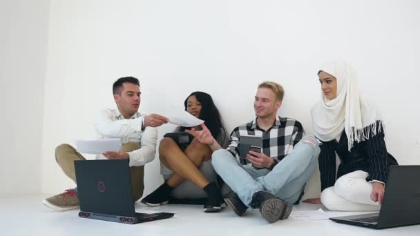 Front view of responsible young creative office group of two men and two mixed race women which sitting on the floor and working with reports and computers — 비디오