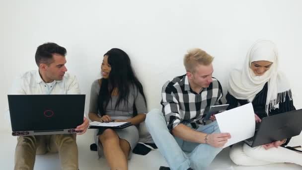 Four creative young modern mixed race office coworkers of men and women which sitting on the floor and discussing business strategy of joint project — ストック動画