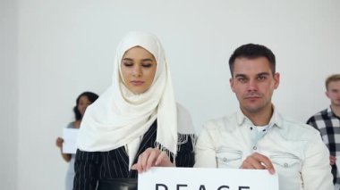 Tesettürlü güzel Müslüman kadın ve Avrupa asıllı ciddi adam el ele tutuşup 