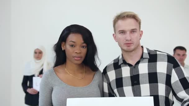 Mujer afroamericana joven seria y hombre europeo sosteniendo en sus manos la inscripción "No racismo" en frente de la mujer musulmana en hiyab y otro tipo europeo con palabras escritas "Love.Happiness " — Vídeo de stock