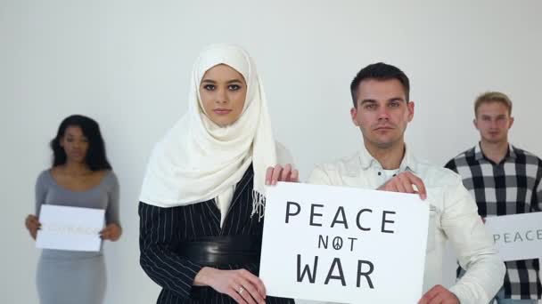Zeitlupe von fokussierten gut aussehenden multirassischen jungen Mann und Frau, die vor der Kamera mit der Aufschrift "Frieden statt Krieg" posieren" — Stockvideo