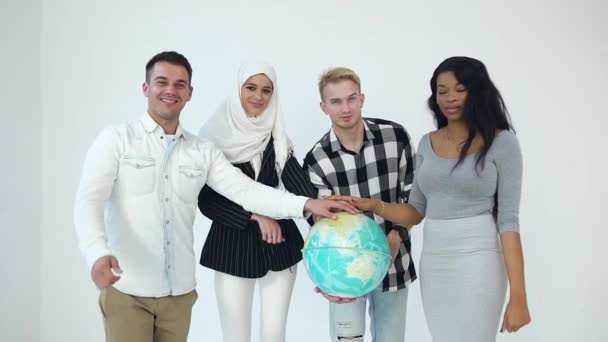 Quatre amis multiethniques souriants heureux mettant une main sur le globe, une autre main montrant le signe OK posant sur la caméra — Video