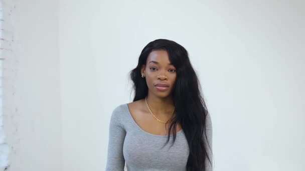 Hermosa joven afroamericana mujer con el pelo largo negro posando en la cámara con globo pequeño y planta verde en sus manos — Vídeo de stock