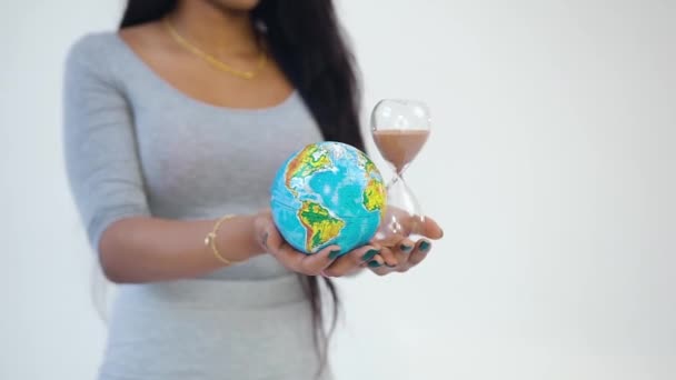 Inconnu jeune femme afro-américaine moderne tenant dans ses mains horloge de sable et petit globe — Video