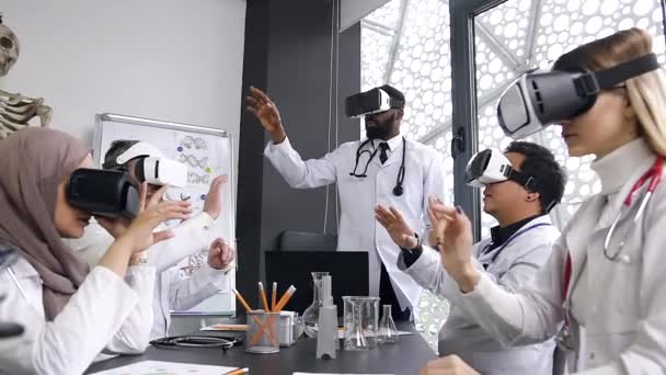 Equipo de médicos multirraciales que usan gafas de realidad aumentada que trabajan en el gabinete interior del hospital — Vídeo de stock