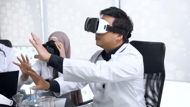 Привабливий портрет азіатських молодих чоловіків і мусульманських медичних працівників, які носять гарнітуру віртуальної реальності, щоб допомогти їм провести медичну процедуру — стокове відео