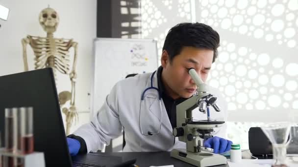 Attraente contento giovane asiatico medico operaio guardando al microscopio in laboratorio e poi mostrando segno OK per la fotocamera — Video Stock