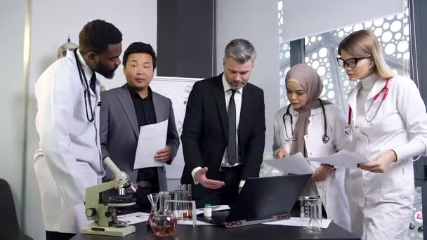 Imagem atraente do grupo de pessoas médicas multirraciais de boa aparência que discutem os problemas reais de medicina na sala de reuniões — Vídeo de Stock