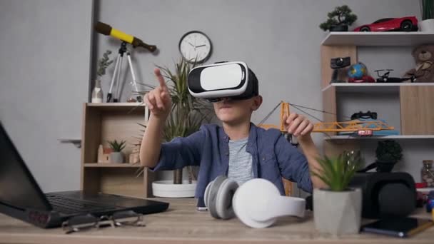 Vista frontal de un agradable adolescente moderno en auriculares de realidad virtual que juegan videojuegos en casa — Vídeo de stock