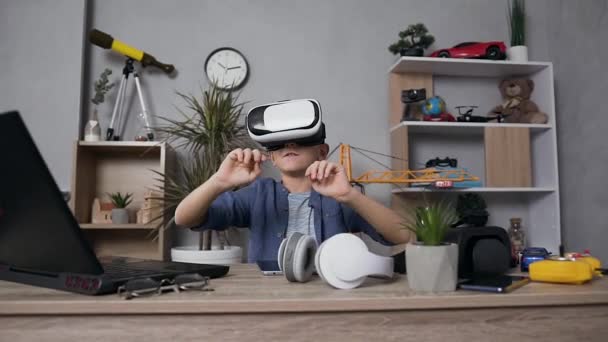 Close view of good-looking 12-aged boy in blue shirt which wearing augmented reality glasses during playing video game — Stock Video