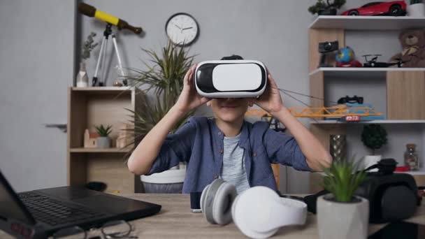 Pleasant smiling teen boy looking at camera and wearing virtual reality headset to play video games — Stock Video